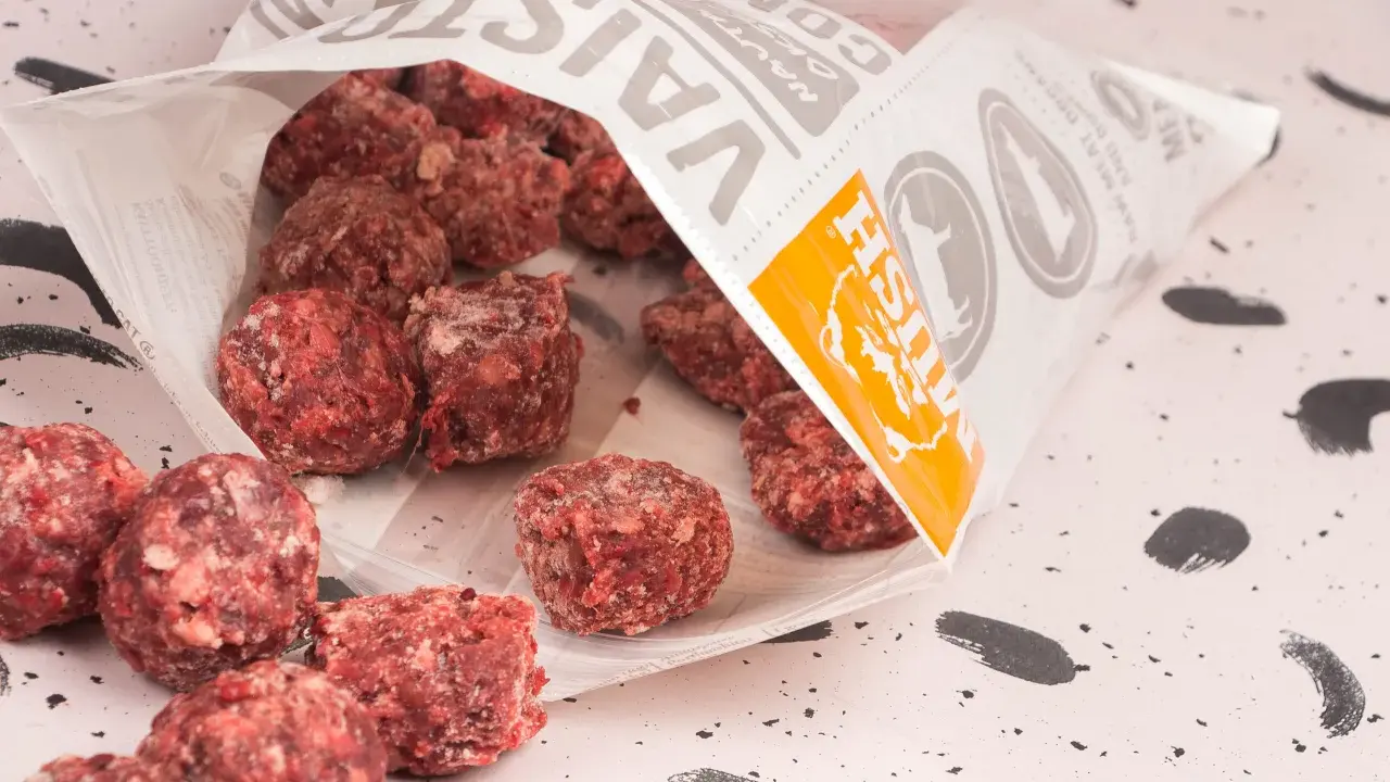 Fryst barf hundmat i form av köttbullar som vält ut ur en påse.