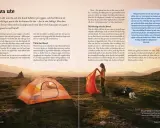En kvinna sätter upp ett tält i ett naturskönt landskap, med en hund som vilar bredvid. Perfekt för vandra med hund.