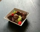En skål med matberikning för hund: köttbitar, kiwi och jordgubbar. En näringsrik och god måltid för din fyrbenta vän.