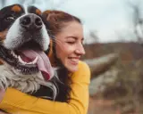 Glad kvinna kramar en stor hund. En perfekt storlek för en trogen vän, som en del av en storleksguide hundraser.