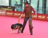 En person klädd som cowboy med en hund som utför ett trick. En del av en hund tricks list.