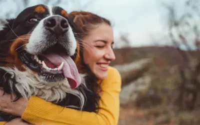 Glad kvinna kramar en stor hund. En perfekt storlek för en trogen vän, som en del av en storleksguide hundraser.
