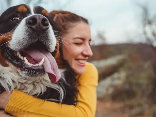 Glad kvinna kramar en stor hund. En perfekt storlek för en trogen vän, som en del av en storleksguide hundraser.