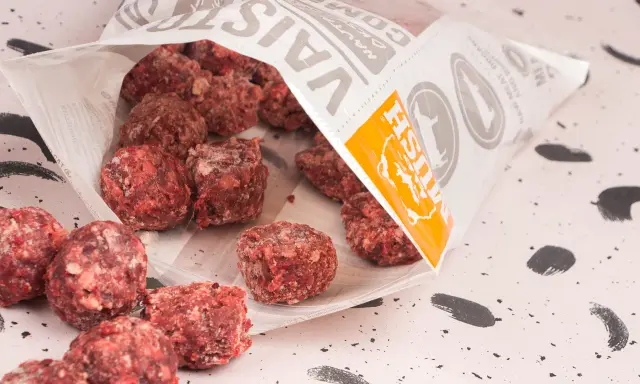 Fryst barf hundmat i form av köttbullar som vält ut ur en påse.