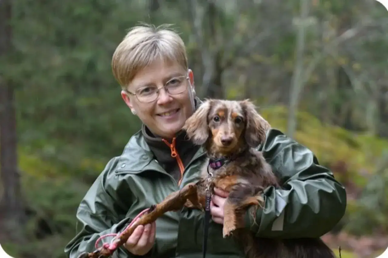 Glad kvinna med tax i famnen, redo för viltspårskurs i skogen.